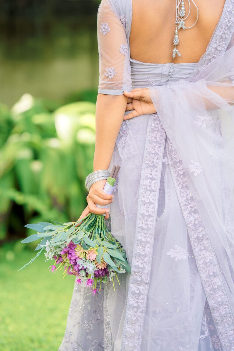 Back view of a bride wearing a blue saree holding fresh flowers