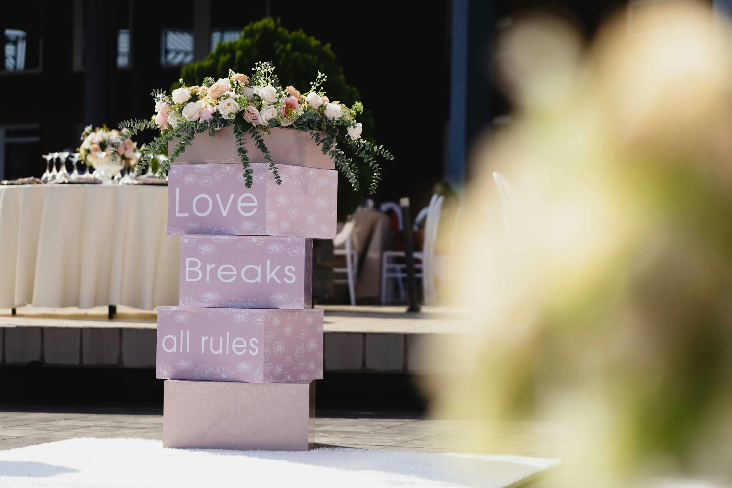 Home Outdoor wedding setting with floral decorations and "Love Breaks all rules" signage.