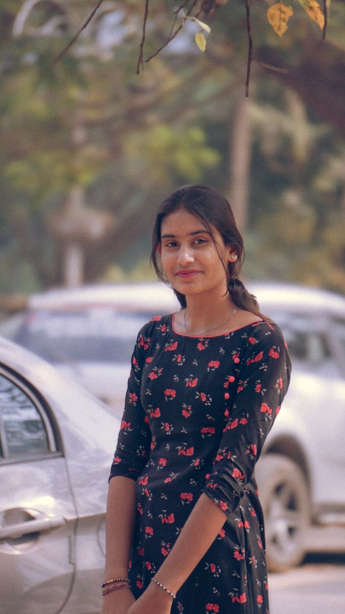 Woman in a black floral dress standing outdoors, exuding elegance and natural beauty.